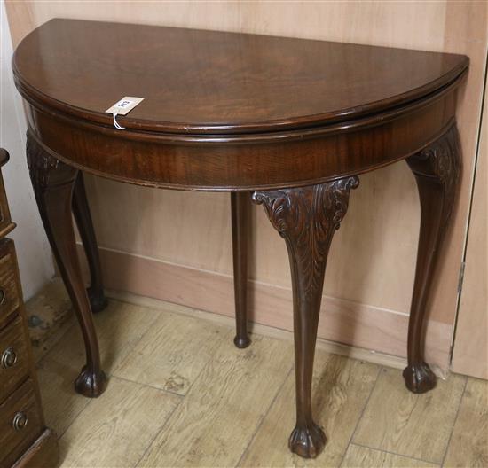 A 1930s carved mahogany demi-lune folding tea table, W.92cm